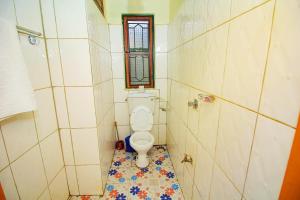 a small bathroom with a toilet and a window at Kenthill Guest House in Jinja