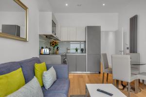 a living room with a blue couch and a kitchen at Regent's Park Serviced Apartments by MySquare in London