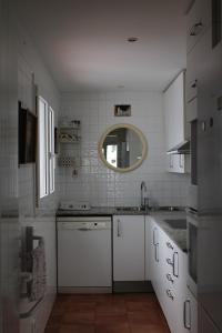 a white kitchen with a sink and a mirror at Attic in Cadaques in Cadaqués