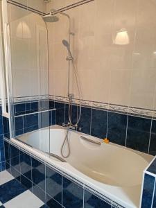 uma banheira na casa de banho com azulejos azuis em Les chambres du Vert Galant Le lever du soleil em Verlinghem