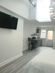 een witte kamer met een flatscreen-tv aan de muur bij The Bay Studio 1 in Broadstairs