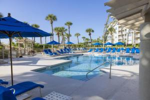 a large swimming pool with blue chairs and umbrellas at 5506 Hampton Place South in Hilton Head Island