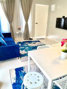 HZ HOMESTAY PENDANG في Pendang: غرفة معيشة مع أريكة وطاولة وكراسي