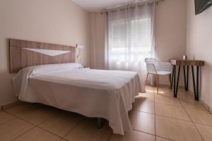 唐貝尼托的住宿－Hotel Tierra，卧室配有床、椅子和窗户。