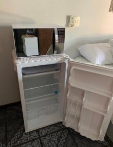 an empty refrigerator with its door open in a room at Suíte Aconchego in Blumenau