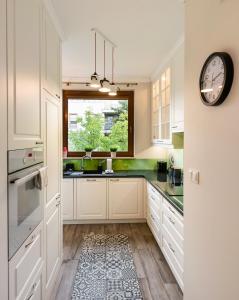 a kitchen with white cabinets and a clock on the wall at Prestige Verdant Apartment in Warsaw