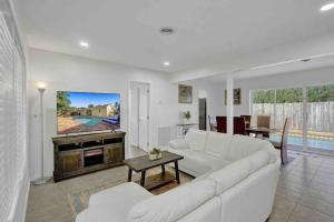 uma sala de estar com um sofá branco e uma televisão em Beautiful 4 Bedrooms/Pool/Walk to beach em Deerfield Beach
