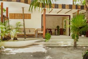a house with a porch with a couch and palm trees at Dos Ceibas Tulum Feel Good Hotel in Tulum
