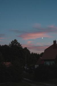 einen Sonnenuntergang mit dem Mond am Himmel über einem Haus in der Unterkunft Przystawy Agroturystyka in Malechowo