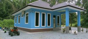 a small blue house with a tractor in front of it at HOMESTAY PAK TEH in Kota Bharu