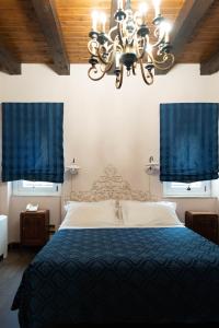 a bedroom with a bed with blue curtains and a chandelier at Hotel Villa Dorata in Nicolosi