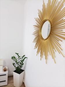 a gold sunburst mirror hanging on a white wall at Soft Apartments in Galaţi