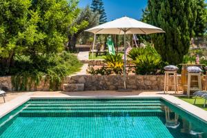 una piscina en un patio con sombrilla en Puig d'en Guardiola en Moscari