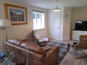 uma sala de estar com um sofá de couro castanho e cadeiras em Canal View em Todmorden
