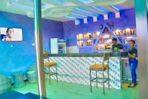 2 personnes debout à un bar dans une pièce bleue dans l'établissement Golden Castle Hotel Hoima, à Hoima