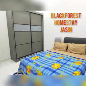 ein Schlafzimmer mit einem Bett mit einer blauen und gelben Decke in der Unterkunft HOMESTAY JASIN BLACKFOREST in Jasin