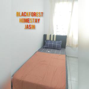 Bett in einem Zimmer mit einem Schild, das den schwarzen Wald-Homiversary Jason liest in der Unterkunft HOMESTAY JASIN BLACKFOREST in Jasin