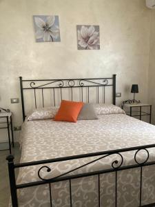 łóżko z pomarańczową poduszką i trzy zdjęcia na ścianie w obiekcie A CASA DI ROSY w mieście Campobasso
