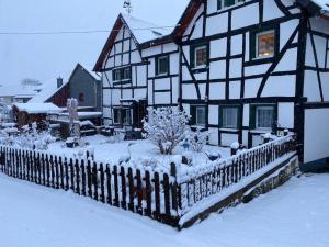 a black and white house with a fence in the snow at Naturnah in Hellenthal in Hellenthal