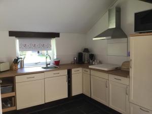une cuisine avec des armoires blanches, un évier et une fenêtre dans l'établissement Landelijk gelegen Huisje op erf, à Veeningen 24 autres photos