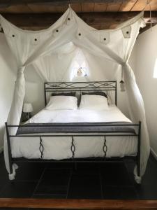 - une chambre avec un lit à baldaquin et des draps blancs dans l'établissement Landelijk gelegen Huisje op erf, à Veeningen