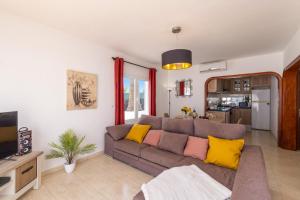 ein Wohnzimmer mit einem grauen Sofa und gelben Kissen in der Unterkunft Villa Almar by Villa Plus in Tías