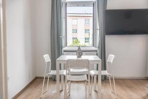 a dining room table with white chairs and a window at Welcoming 2BR Apt. near AKH- Perfect for Longstays in Vienna