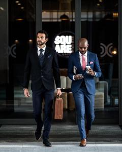 two men in suits walking down the street at Century City Hotel Urban Square in Cape Town