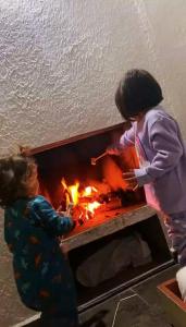 dos niños parados junto a un fuego en una chimenea en Pousada Green Valley, en São Roque