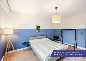 ein Schlafzimmer mit einem Bett und einer blauen Wand in der Unterkunft Becozy Self Check-in Hotel Basel an der Messe in Basel