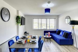 a living room with a table and a blue couch at Spacious - PENTHOUSE 2 Bed Apartment with secure allocated parking in Sheffield