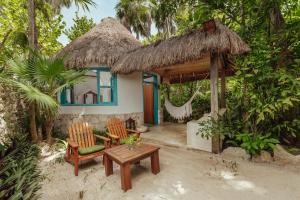 Dos Ceibas Tulum Feel Good Hotel في تولوم: منزل به كرسيين وطاولة وأرجوحة