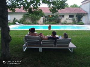eine Gruppe von Menschen, die auf einer Bank am Pool sitzen in der Unterkunft Domaine de Cremens 
