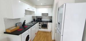 a kitchen with white cabinets and a white refrigerator at Garland Modern Central City Apartment London in London
