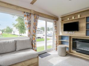 uma sala de estar com um sofá, uma televisão e uma lareira em 28 Coniston em Grange Over Sands