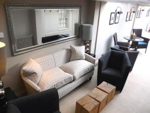 a living room with a couch and chairs and a mirror at Manor Green Cottage in Windsor