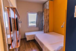 a small room with two beds and a window at Ibis Budget Lorena - Circuito da Fé in Lorena
