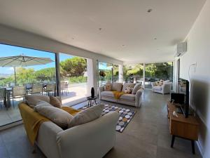 a living room with two couches and a tv and glass doors at Villa 6 Chambres, Piscine, vue Mer, à Proximité de la Plage , Cavalaire-sur-mer in Cavalaire-sur-Mer