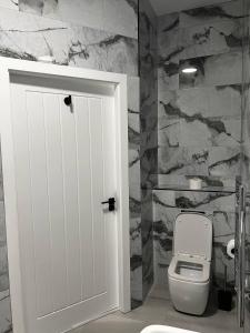 a bathroom with a toilet and a stone wall at Spire Accommodations Ltd in Bradford