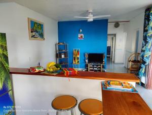 a kitchen with a counter with stools and a blue wall at Luketo in Vieux-Habitants