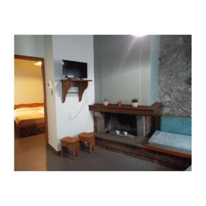 a living room with a fireplace and a bed at Potamolithos Suites in Konitsa