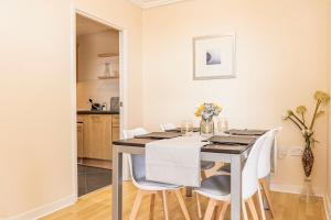 a dining room with a table and white chairs at Oakdale Apartments in Woking