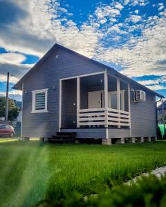 une maison grise avec une terrasse couverte et une pelouse dans l'établissement Szary Domek w Karkonoszach, à Podgórzyn