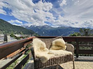 een rieten stoel op een balkon met uitzicht op de bergen bij Crépuscule 5 in Verbier