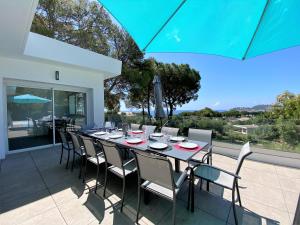 uma mesa de jantar e cadeiras num pátio com um guarda-sol em Villa 6 Chambres, Piscine, vue Mer, à Proximité de la Plage , Cavalaire-sur-mer em Cavalaire-sur-Mer