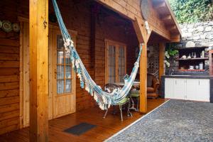 un porche con hamaca en una cabaña de madera en Casas Maravilha by Madeira Sun Travel, en Calheta