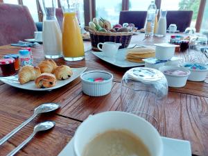 a wooden table with plates of pastries and a cup of coffee at Chambres d'hôtes chez l'habitant - Bed & Breakfast homestay in Huisnes-sur-Mer