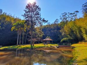 a pond with a gazebo next to a forest at Pousada Green Valley in São Roque