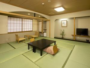 een kamer met een tafel en stoelen en een televisie bij Kyoto Ryokan Hirashin in Kyoto