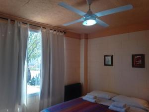 1 dormitorio con ventilador de techo y 1 cama con ventana en Aquamarinas Departamentos en Playas Doradas